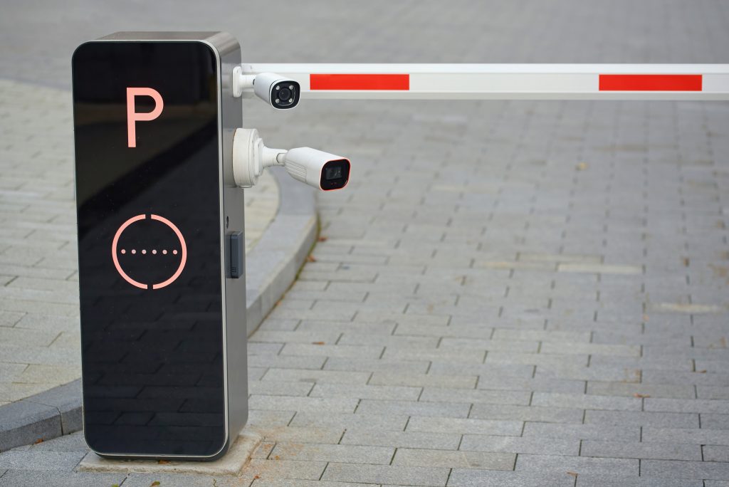 Two digital security cameras installed at a restricted parking entrance for vehicle surveillance close-up. Smart security cameras integrated with parking barrier system for automated access control