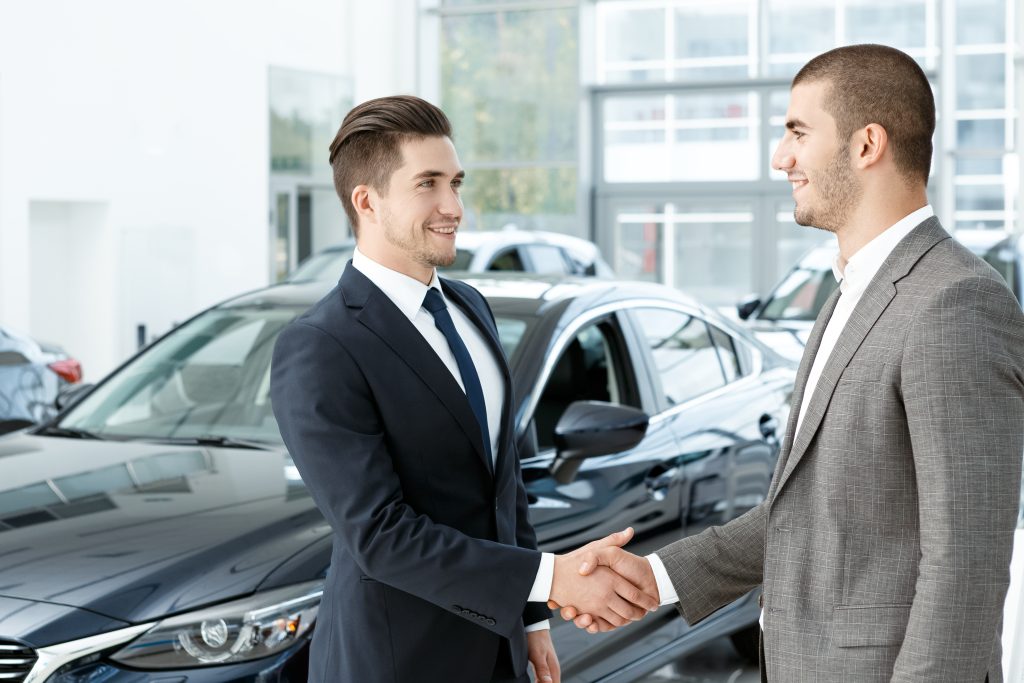 Congratulations. Horizontal portrait of a young businessman shaking hands with the car dealer after a successful deal