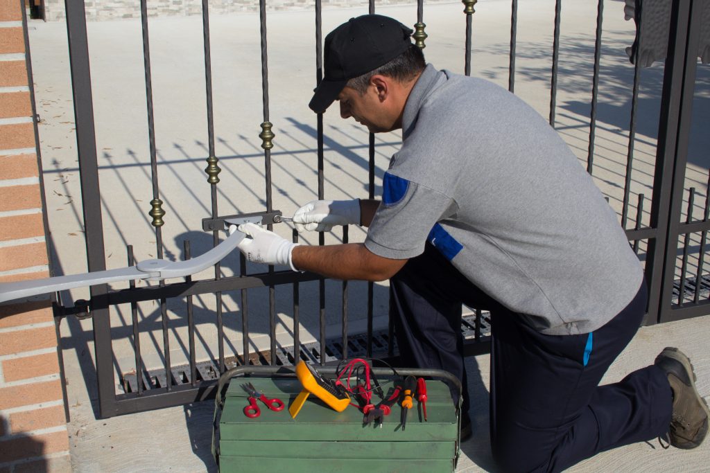 Electrician at work with tools of the trade while assembling and repairing the motor of an automatic gate. Do it yourself homework