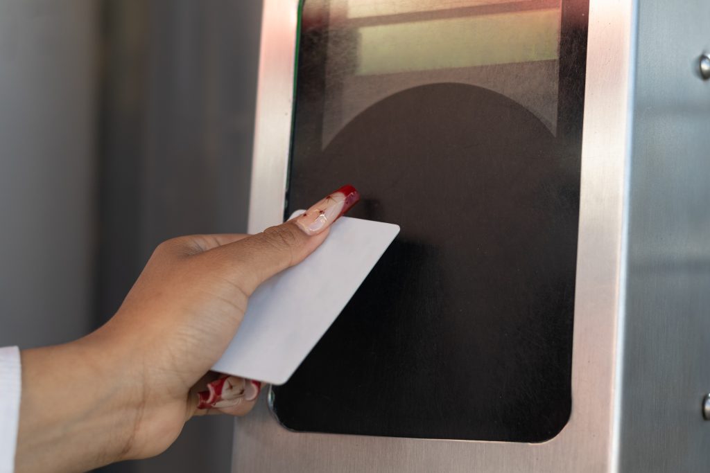 Horizontal photograph of the hand of a woman who is traveling, paying her transportation service ticket at the automatic control with her card to access the bus