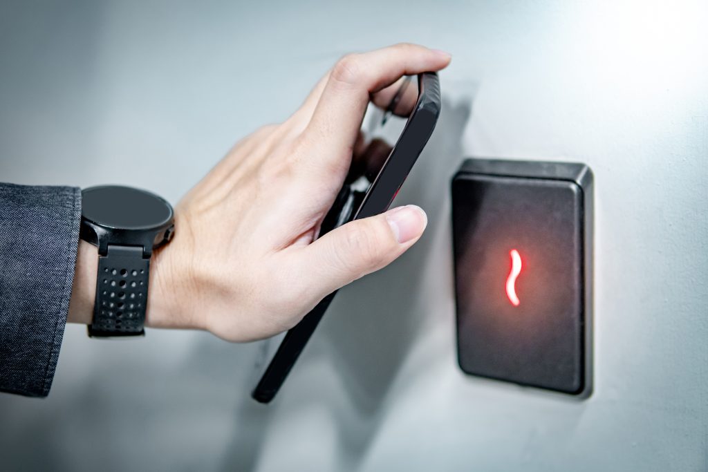 Male hand using smartphone for sensor scanning. Infrared sensor technology for automatic door access and security.