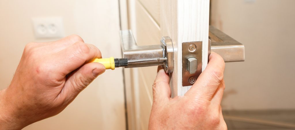 Man is installing the doors handle. Repair works. Maintenance in the apartment.